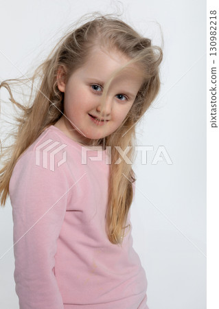 A cheerful girl dressed in a pink sweater with her hair blowing beautifully in the wind A cheerful girl dressed in a pink sweater with her hair blowing beautifully in the wind 130982218