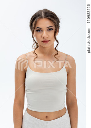 Trendy Young Woman Showcasing a Stylish and Fashionable Outfit Set Against a White Background Trendy Young Woman Showcasing a Stylish and Fashionable Outfit Set Against a White Background 130982226