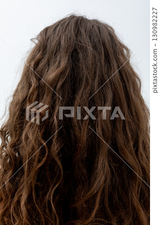 This stunning and beautiful back view features curly hair illuminated in soft, gentle light 130982227