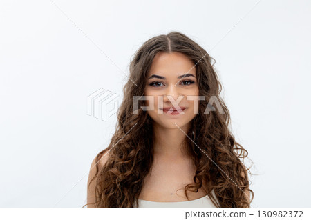 A Cheerful Smiling Woman with Curly Hair Posed in a Bright and Appealing Studio Setting 130982372