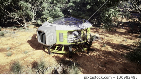 A futuristic habitat is situated in a dense forest. The circular structure features large windows and sits on a raised platform, surrounded by various plants and trees, creating a secluded atmosphere. 130982483