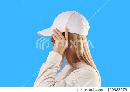 Woman adjusts her white cap while wearing a matching sweatshirt 130982879