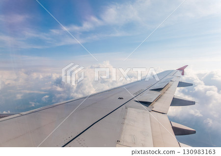 View from the airplane window at a beautiful cloudy sky and the airplane wing 130983163