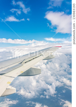 View from the airplane window at a beautiful cloudy sky and the airplane wing View from the airplane window at a beautiful cloudy sky and the airplane wing 130983193