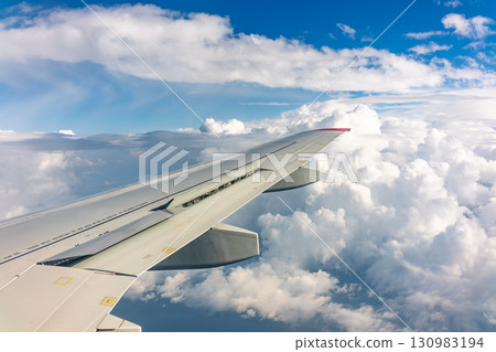 View from the airplane window at a beautiful cloudy sky and the airplane wing View from the airplane window at a beautiful cloudy sky and the airplane wing 130983194