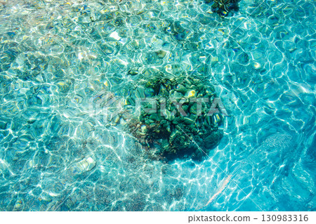 Tourists are landing on the white sand beach of Kabi Island. A beautiful coral reef with parasols, boats, and sabani boats moored. Tourists are landing on the white sand beach of Kabi Island. A beautiful coral reef with parasols, boats, and sabani boats moored. 130983316