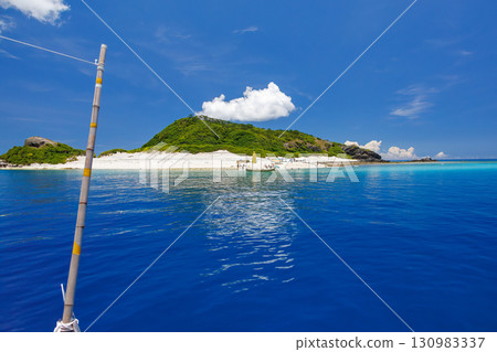 遊客登上卡比島的白色沙灘。美麗的珊瑚礁，停泊著遮陽傘、船和鰹魚船。 130983337