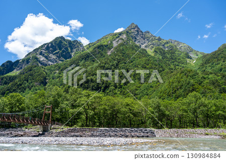 Myojin Bridge and mountains along Kamikochi hiking trail, Japan Myojin Bridge and mountains along Kamikochi hiking trail, Japan 130984884