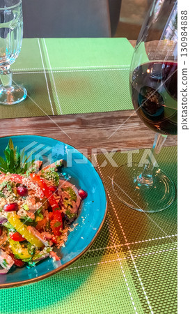 Fresh vegetable salad and a glass of red wine on the table. Fresh vegetable salad and a glass of red wine on the table. 130984888