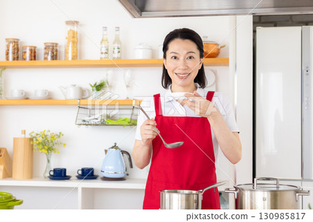 Housekeeping service: Middle-aged woman cooking 130985817