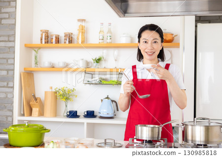 Housekeeping service: Middle-aged woman cooking Housekeeping service: Middle-aged woman cooking 130985818