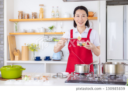 Housekeeping service: Middle-aged woman cooking Housekeeping service: Middle-aged woman cooking 130985839