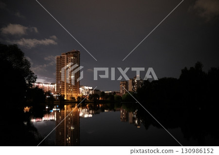 A city building built on the shore of a reservoir at night 130986152