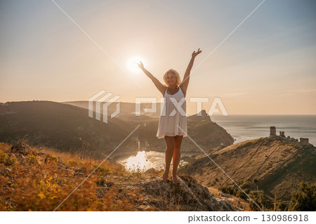 woman standing hill with her arms raised in the air, looking up at the sun. The scene is peaceful and serene, with the woman's expression conveying a sense of joy and happiness. woman standing hill with her arms raised in the air, looking up at the sun. The scene is peaceful and serene, with the woman's expression conveying a sense of joy and happiness. 130986918