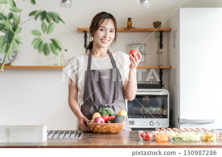 亞洲婦女在廚房拿著蔬菜,家庭主婦 亞洲婦女在廚房拿著蔬菜,家庭主婦 130987286