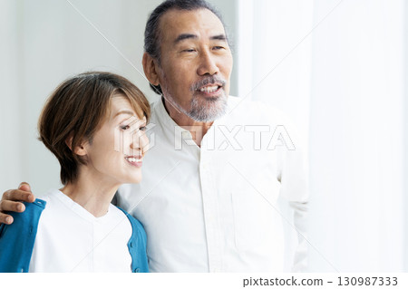 Senior couple standing by the window 130987333