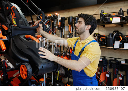 A man choosing a lawn mower inside a retail store 130987407