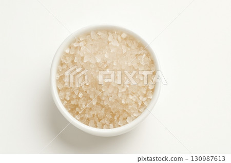 Coarse sea salt crystals in white bowl on white background 130987613