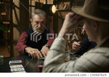 Live poker game featuring company of men with cigar and alcohol beverages 130987629