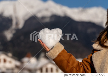 Snow Heart Mountains Winter: Romantic snow heart held in hand, winter mountains background, showcasing love in snowy Alps. Snow Heart Mountains Winter: Romantic snow heart held in hand, winter mountains background, showcasing love in snowy Alps. 130987722