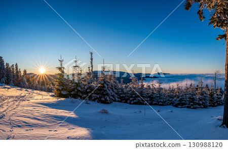 Panoramic view from Pancir mountain in Sumava national park with hills and forests rising above valleys filled with fog during sunset, creating a magical inversion landscape. 130988120