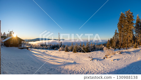 Panoramic view from Pancir mountain in Sumava national park with hills and forests rising above valleys filled with fog during sunset, creating a magical inversion landscape. 130988138