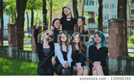Group of seven stylish young women gather on a bench outside their high school, basking in the sunshine and each other's company Group of seven stylish young women gather on a bench outside their high school, basking in the sunshine and each other's company 130988168