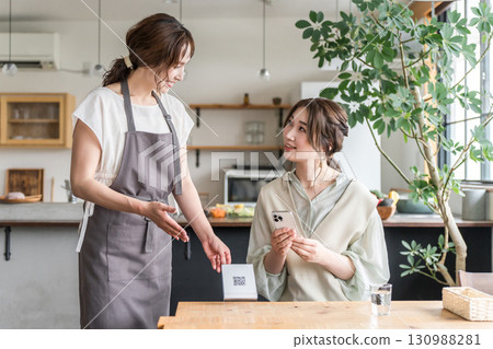 一名服務生在咖啡館出示二維碼，一名女顧客正在操作智慧型手機 130988281