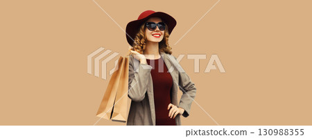 Autumn portrait of beautiful young woman with shopping bag, stylish girl in coat on brown background Autumn portrait of beautiful young woman with shopping bag, stylish girl in coat on brown background 130988355