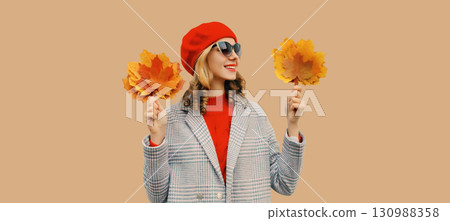 Autumn portrait of beautiful happy smiling woman with yellow maple leaves in red french beret hat 130988358