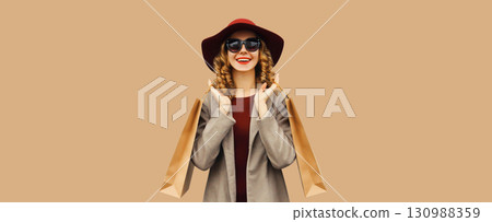 Autumn portrait of beautiful young woman with shopping bag, stylish girl in coat on brown background 130988359