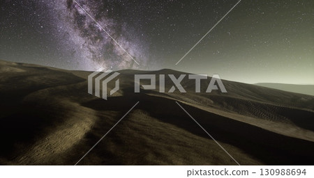 Vast desert dunes stretch under a star filled night sky showcasing the grandeur of the Milky Way. The gentle curves of the terrain blend with the cosmic display above, creating a serene vista. Vast desert dunes stretch under a star filled night sky showcasing the grandeur of the Milky Way. The gentle curves of the terrain blend with the cosmic display above, creating a serene vista. 130988694