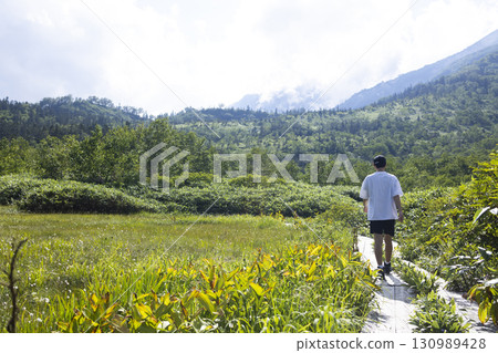 Man hiking on a boardwalk Man hiking on a boardwalk 130989428