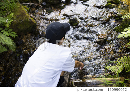 A boy cooling his hands with spring water 130990052
