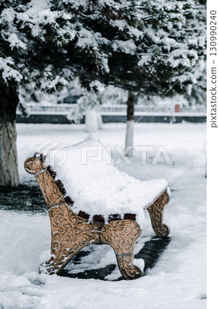 Snowy bench in winter park. 130990240