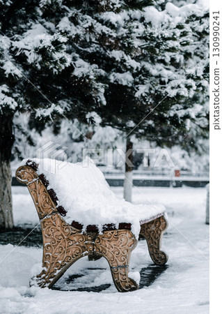 Snowy bench in winter park. 130990241