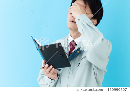 A middle-aged male businessman in work clothes worried about his notebook A middle-aged male businessman in work clothes worried about his notebook 130990807