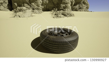 A lone tire lies on the sandy ground, surrounded by textured rocks under a blue sky, indicating a remote location possibly affected by abandonment or a vehicle breakdown. A lone tire lies on the sandy ground, surrounded by textured rocks under a blue sky, indicating a remote location possibly affected by abandonment or a vehicle breakdown. 130990927
