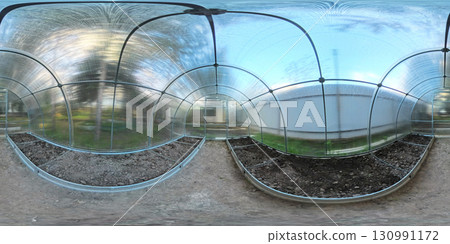 A 360-degree view inside a clear polycarbonate greenhouse with arched frames. Soil beds are prepared on both sides of the central path, ready for planting. Bright natural light fills the space. A 360-degree view inside a clear polycarbonate greenhouse with arched frames. Soil beds are prepared on both sides of the central path, ready for planting. Bright natural light fills the space. 130991172