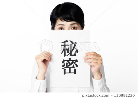 一位年長的女人從一張寫著「秘密」的紙後面往外看 130991220