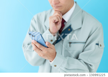 一位身穿工作服的中年男性商人看著他的智慧型手機，擔心 130991225