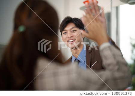 Positive Interaction. Colleague sharing a high-five in a professional setting. 130991373