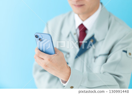 一位身著工作服的中年男性商人用智慧型手機拍照 一位身著工作服的中年男性商人用智慧型手機拍照 130991448