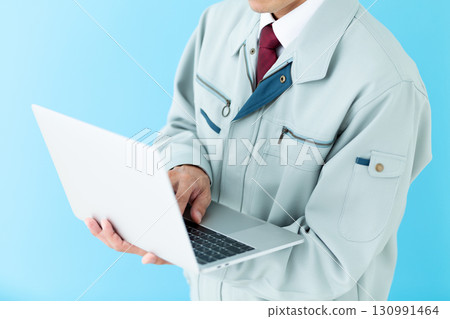 一位身著工作服的中年男性商人拿著一台筆記型電腦 一位身著工作服的中年男性商人拿著一台筆記型電腦 130991464