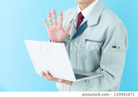 A middle-aged male businessman in work clothes holding a laptop and pointing up five fingers A middle-aged male businessman in work clothes holding a laptop and pointing up five fingers 130991671