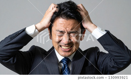 Businessman scratching his head in agony 130993921