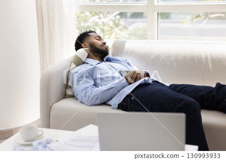 Tired exhausted young man sleep on couch after computer work 130993933