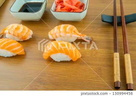 sushi with salmon and shrimp close-up on a wooden background with soy sauce and ginger 130994456