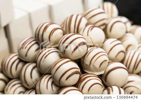 sweets covered with white chocolate and brown lines close-up 130994474