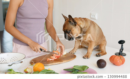 The process of preparing fresh, vibrant ingredients alongside a curious dog in the kitchen The process of preparing fresh, vibrant ingredients alongside a curious dog in the kitchen 130994488